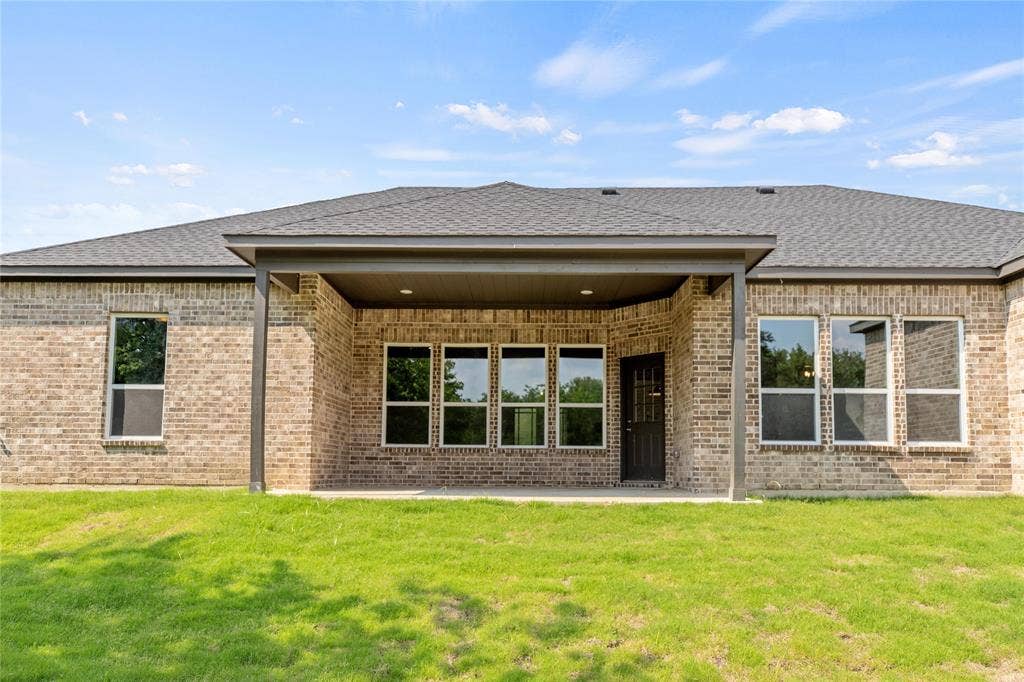 10560 Lago Vista, Quinlan, TX 75474 Rear view of property featuring a patio, brick siding, and a lawn