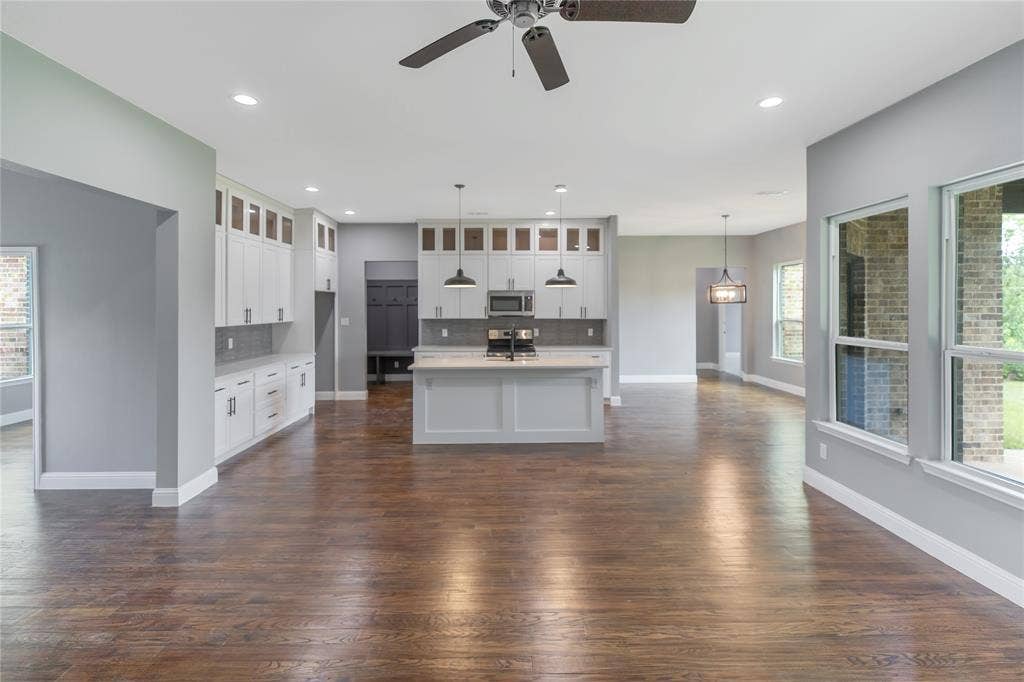 10560 Lago Vista, Quinlan, TX 75474 Kitchen featuring tasteful backsplash, glass insert cabinets, a center island with sink, dark wood finished floors, and ceiling fan
