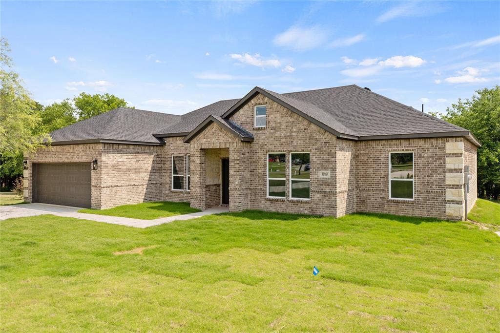 10560 Lago Vista, Quinlan, TX 75474 View of front of house featuring a front yard, brick siding, roof with shingles, a garage, and driveway