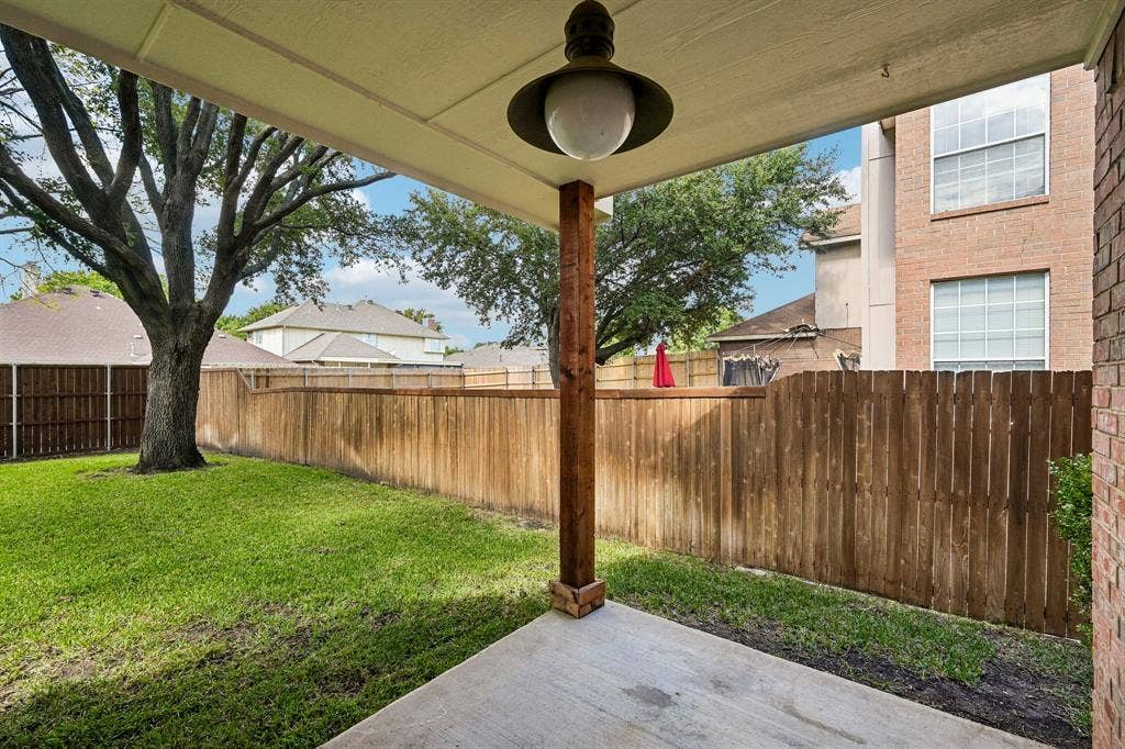 758 Livingston Drive, Allen, TX 75002 Covered patio featuring a concrete floor, a rustic wood support post, and a vintage-style hanging pendant light, opening to a fenced backyard with mature trees