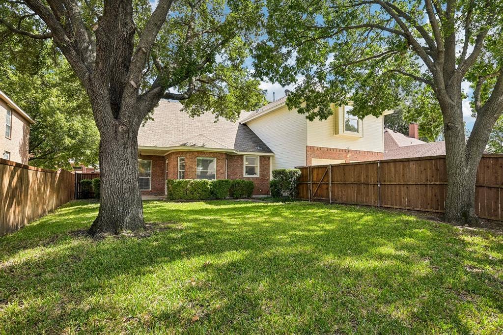 758 Livingston Drive, Allen, TX 75002 Rear exterior featuring a brick and siding facade, a fenced-in yard, and mature shade trees