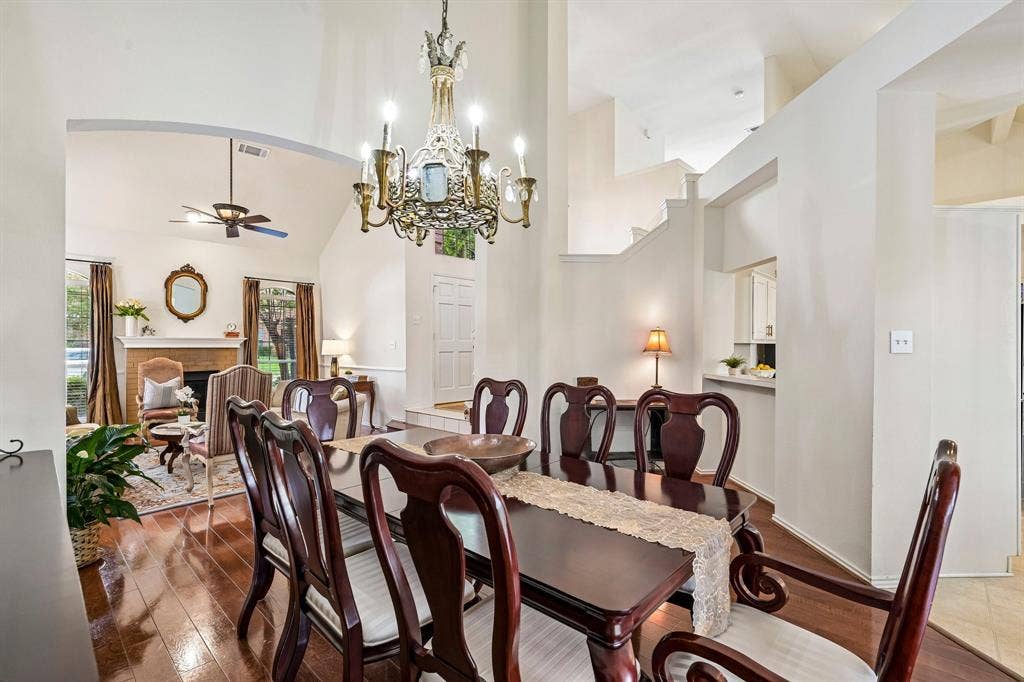 758 Livingston Drive, Allen, TX 75002 High-ceiling dining area featuring wood-finish flooring, an ornate metal chandelier, and a brick-faced fireplace