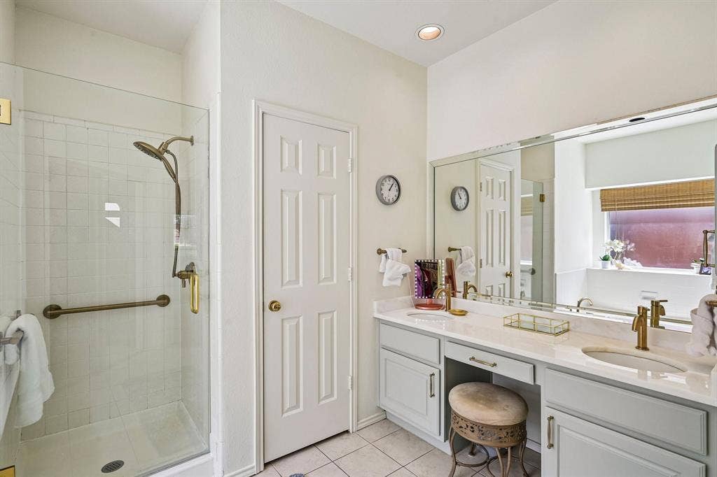 758 Livingston Drive, Allen, TX 75002 Dual-sink vanity with light-tone cabinetry and metallic hardware, glass-enclosed shower with tiled surround, and integrated wall-to-wall vanity mirror