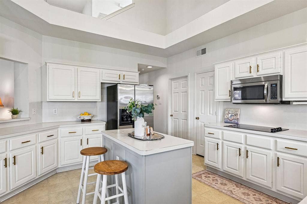 758 Livingston Drive, Allen, TX 75002 Kitchen featuring white cabinetry with gold-tone hardware, central island, high vaulted ceiling, and stainless steel appliances