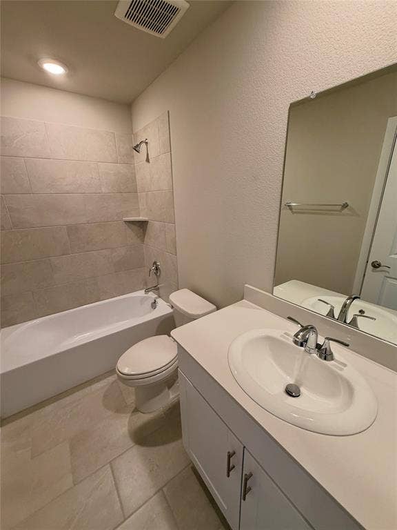 Bathroom featuring a vanity with a solid-surface countertop and integrated sink, a built-in tub with ceramic tile surround, and large-format tile flooring