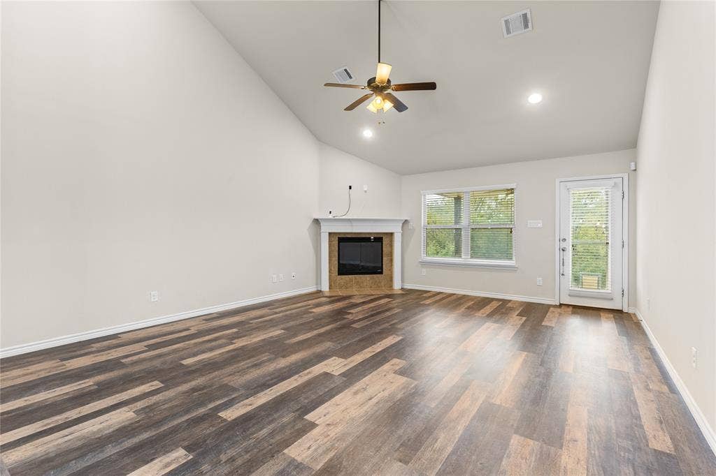 5751 Mountain Hollow Drive, Dallas, TX 75249 Vaulted ceiling featuring a central ceiling fan, wood-finish flooring, and a fireplace with a mantel and tiled surround