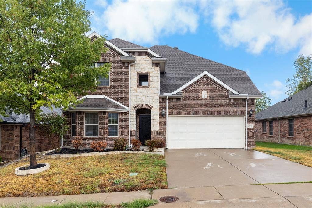 5751 Mountain Hollow Drive, Dallas, TX 75249 Multi-level residence featuring a brick and stone facade, gabled rooflines, two-car garage, and a bay window