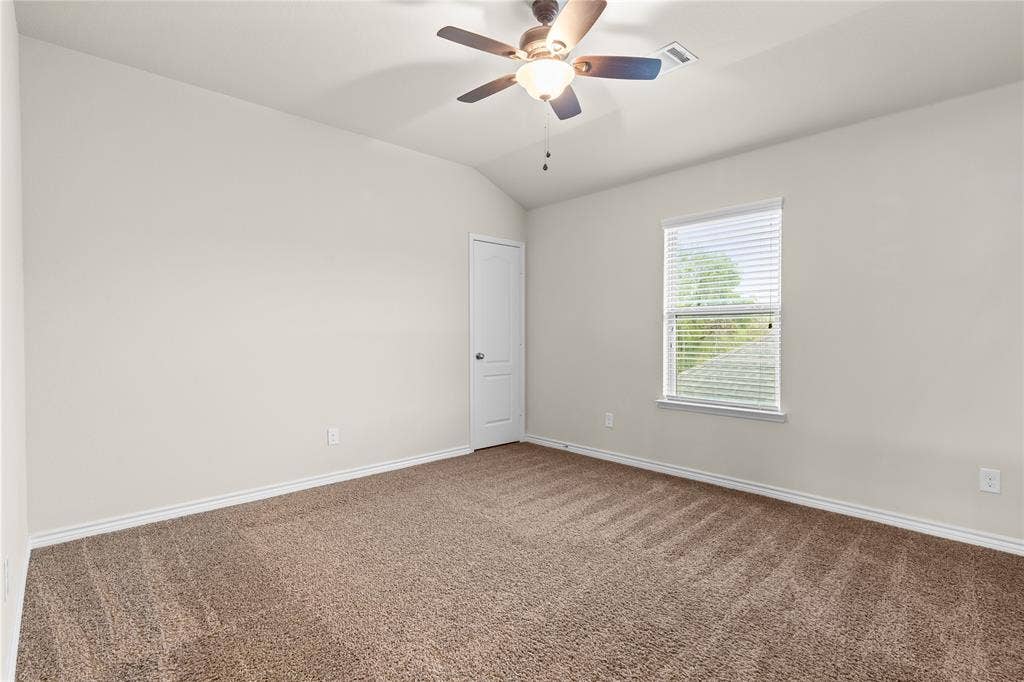 5751 Mountain Hollow Drive, Dallas, TX 75249 Interior room featuring vaulted ceilings, neutral-toned wall paint, wall-to-wall carpeting, an integrated ceiling fan with light fixture, and a single-pane window with horizontal blinds