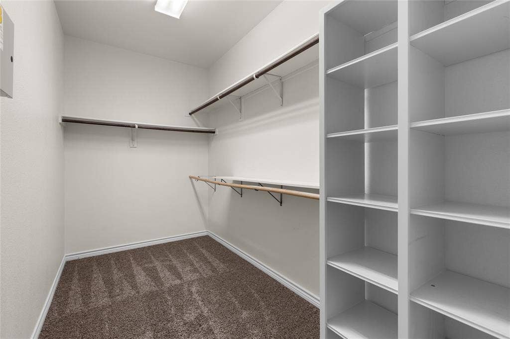 5751 Mountain Hollow Drive, Dallas, TX 75249 Storage area featuring built-in floor-to-ceiling shelving, multiple tiers of hanging rods, and neutral carpeting
