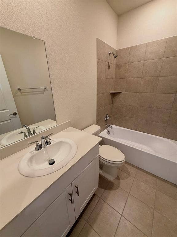 Bathroom featuring a white vanity cabinet with a solid surface countertop, an oval drop-in sink, ceramic tile flooring, and a tub-shower combination with tile surround