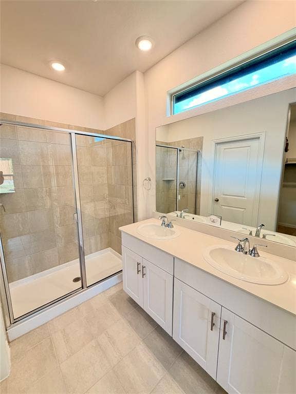 Dual-sink vanity with white cabinetry, neutral solid-surface countertop, glass-enclosed shower with tiled surround, and transom window