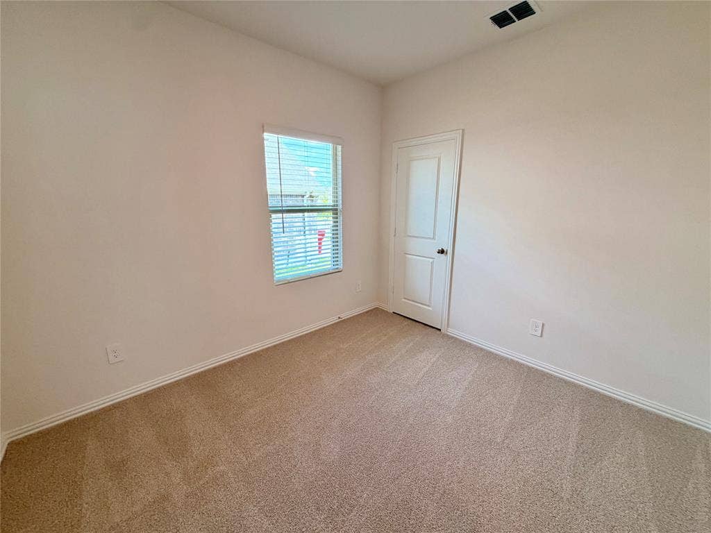 Neutral wall finishes, carpeted flooring, single-panel interior door, and window with horizontal blinds