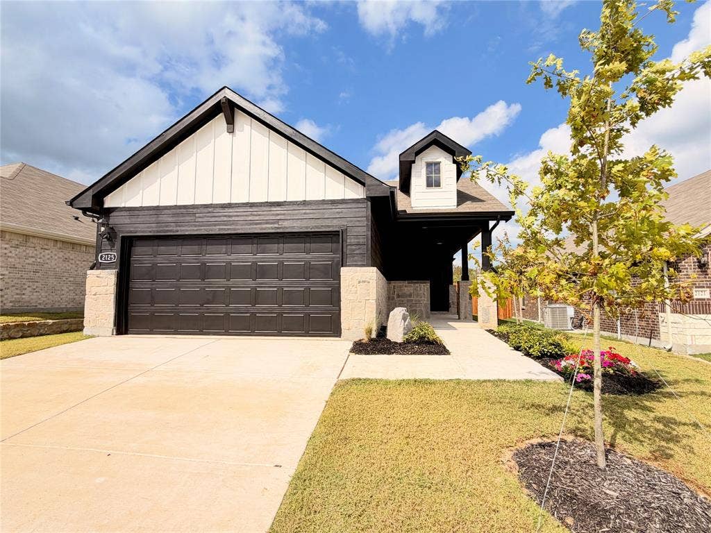 Exterior featuring vertical board-and-batten siding, horizontal wood-finish lap siding, stone veneer accents, and a covered entryway