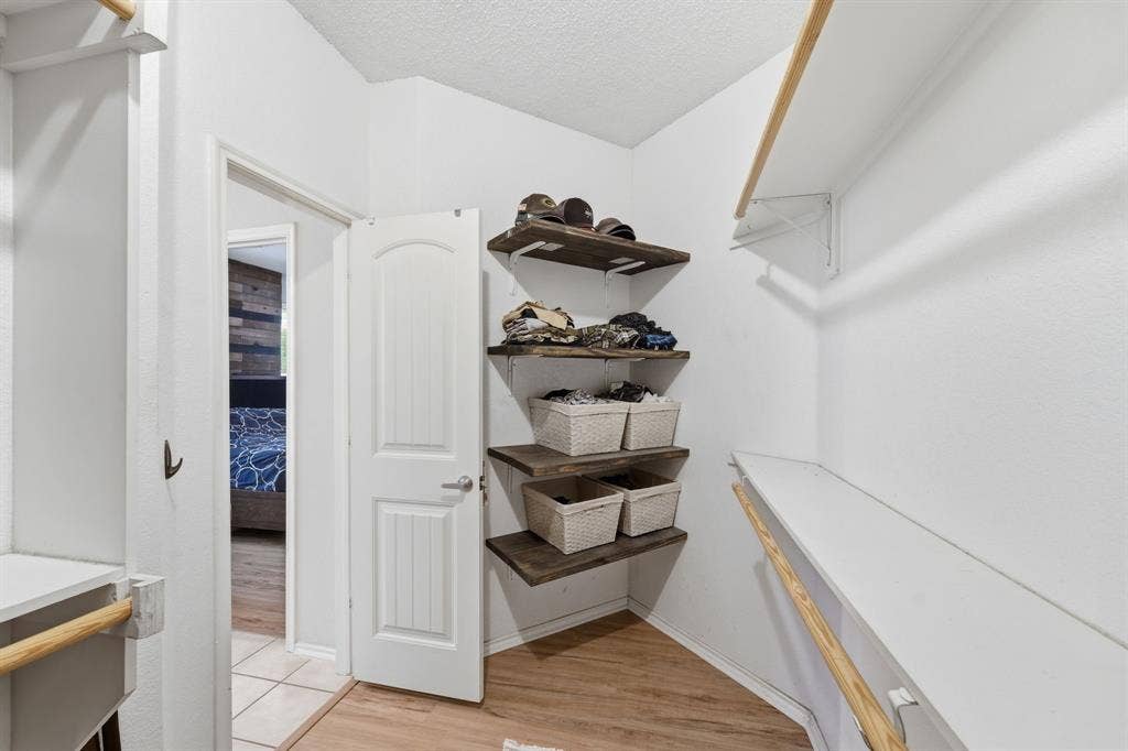 The oversized primary walk-in closet features a ample storage with a custom organization system.