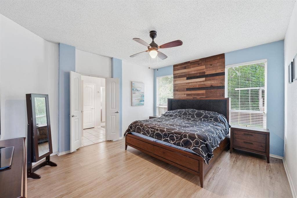 The oversized private, primary bedroom offers tons of natural light, a feature wall and high ceilings.  Photo taken prior to the owner vacating.