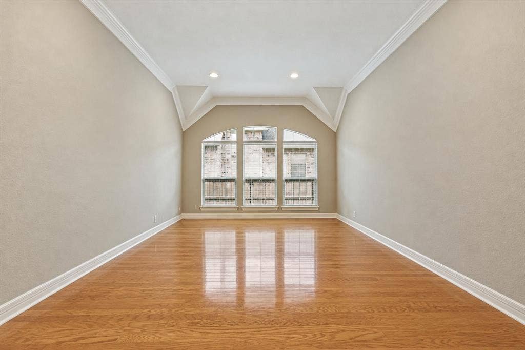 604 Barkley Drive, McKinney, TX 75071 Room featuring polished wood-finish flooring, vaulted ceiling, crown molding, recessed lighting, and a triple-pane arched window