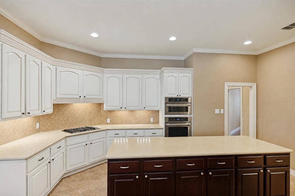 604 Barkley Drive, McKinney, TX 75071 Kitchen featuring crisp white upper cabinetry, a dual-toned kitchen island with dark cabinetry, stone-finish countertops, built-in stainless steel double ovens, and recessed lighting