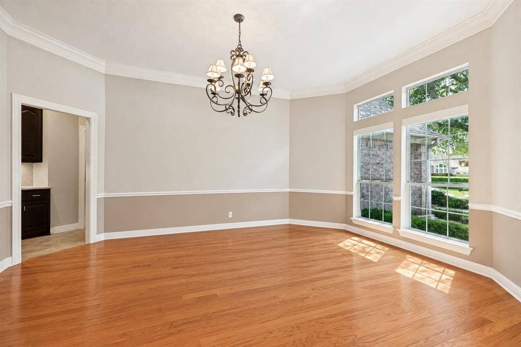 604 Barkley Drive, McKinney, TX 75071 Hardwood flooring, crown molding, chair rail trim, oversized grid-pattern windows, and a multi-arm metal chandelier