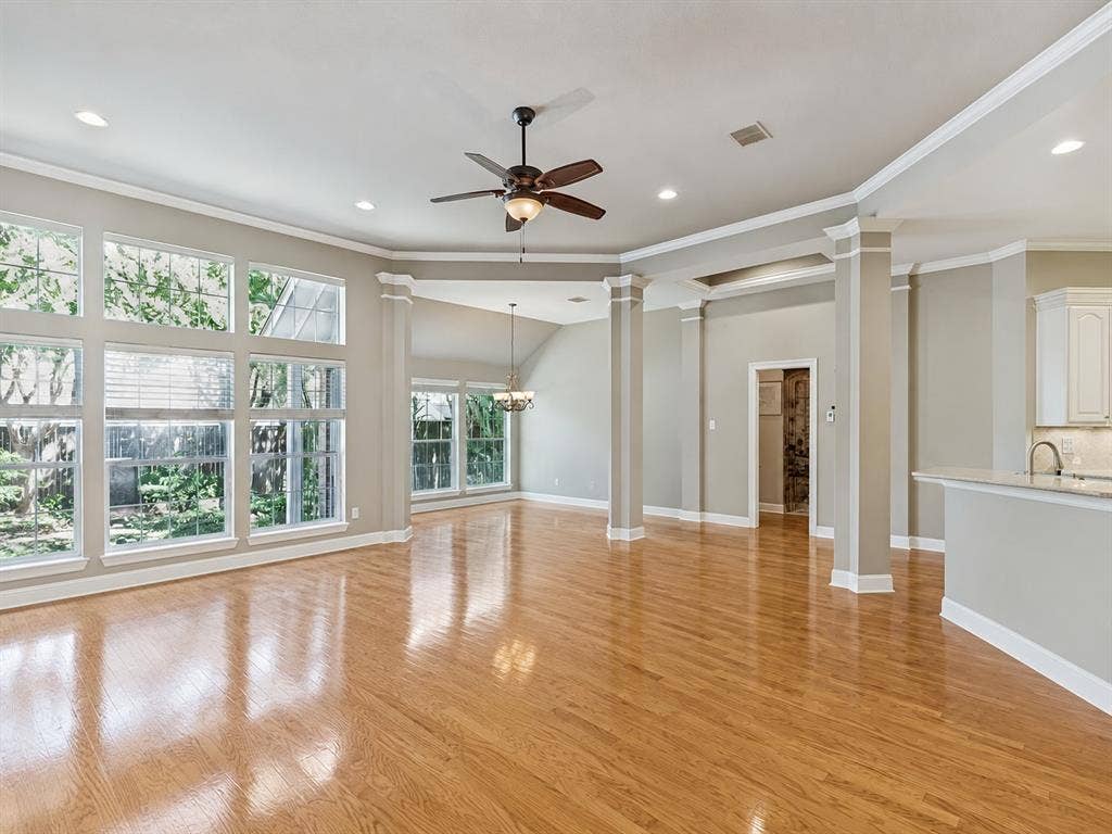 604 Barkley Drive, McKinney, TX 75071 Open-concept living space featuring wood-finish flooring, vaulted ceilings with recessed lighting, prominent architectural columns, and expansive windows