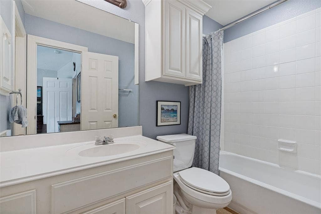 604 Barkley Drive, McKinney, TX 75071 Bathroom featuring a vanity with integrated sink, white cabinetry, large wall-mounted mirror, and a tub enclosure with white tile surround