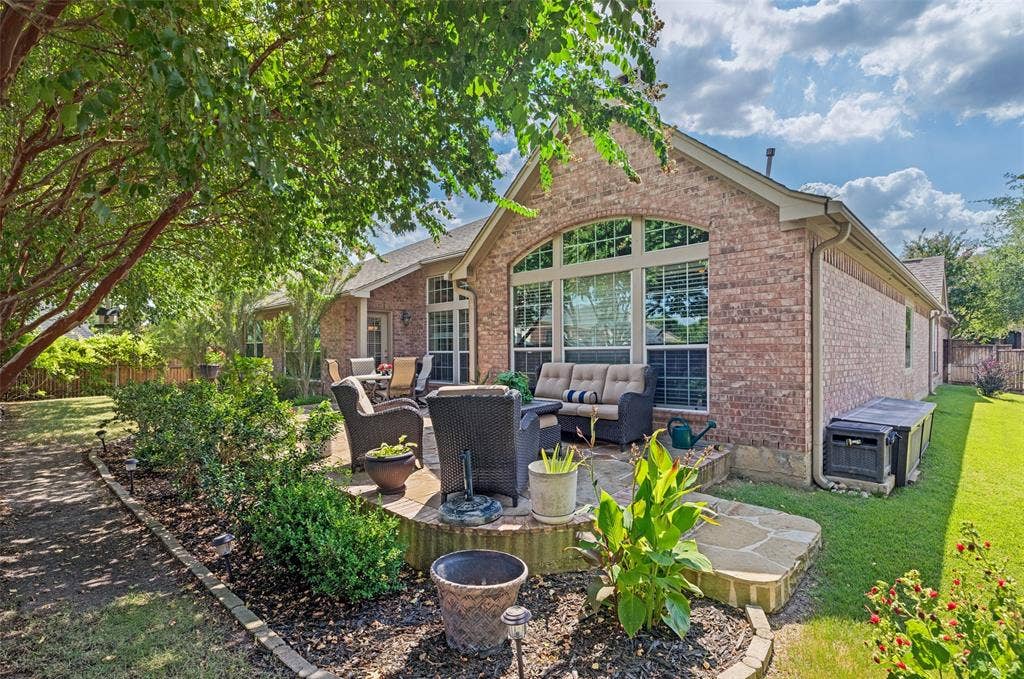 604 Barkley Drive, McKinney, TX 75071 Brick exterior featuring a raised natural stone patio, arched windows with multi-pane glazing, and mature landscaping