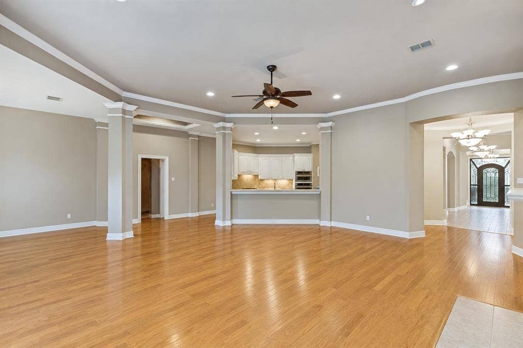 604 Barkley Drive, McKinney, TX 75071 Open-concept interior featuring wood-finish flooring, recessed lighting, decorative pillars, a neutral color palette, and white cabinetry