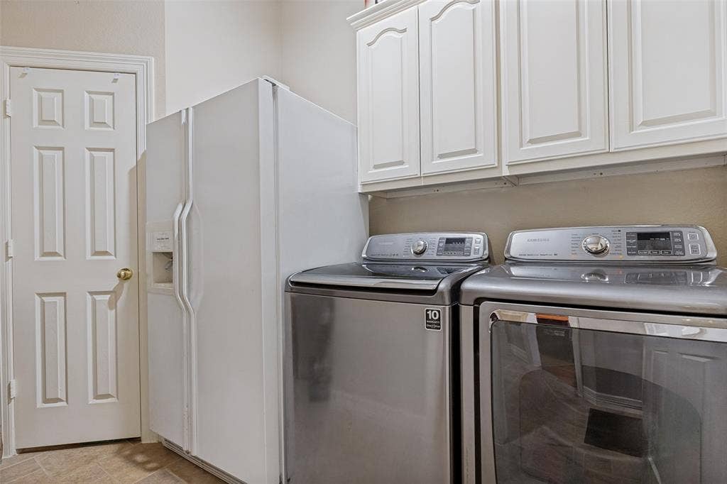 604 Barkley Drive, McKinney, TX 75071 Utility area featuring white raised-panel cabinetry, a side-by-side white refrigerator, and stainless steel washing machine and dryer set