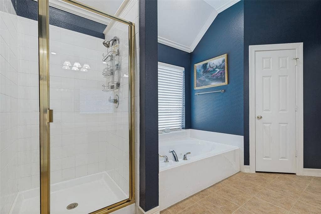 604 Barkley Drive, McKinney, TX 75071 Tiled walk-in shower with gold-tone frame, jetted soaking tub with deck-mounted chrome faucet, vaulted ceiling, and tile flooring