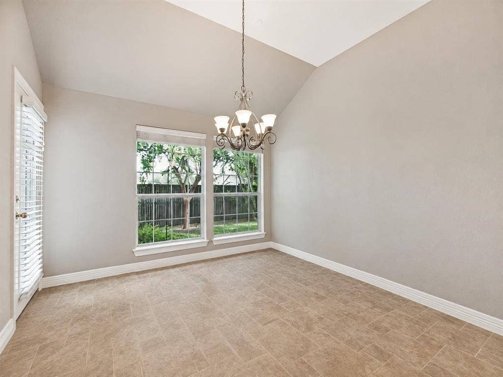 604 Barkley Drive, McKinney, TX 75071 Vaulted ceiling featuring a tiered chandelier, large grid-pane windows, and stone-finish tile flooring