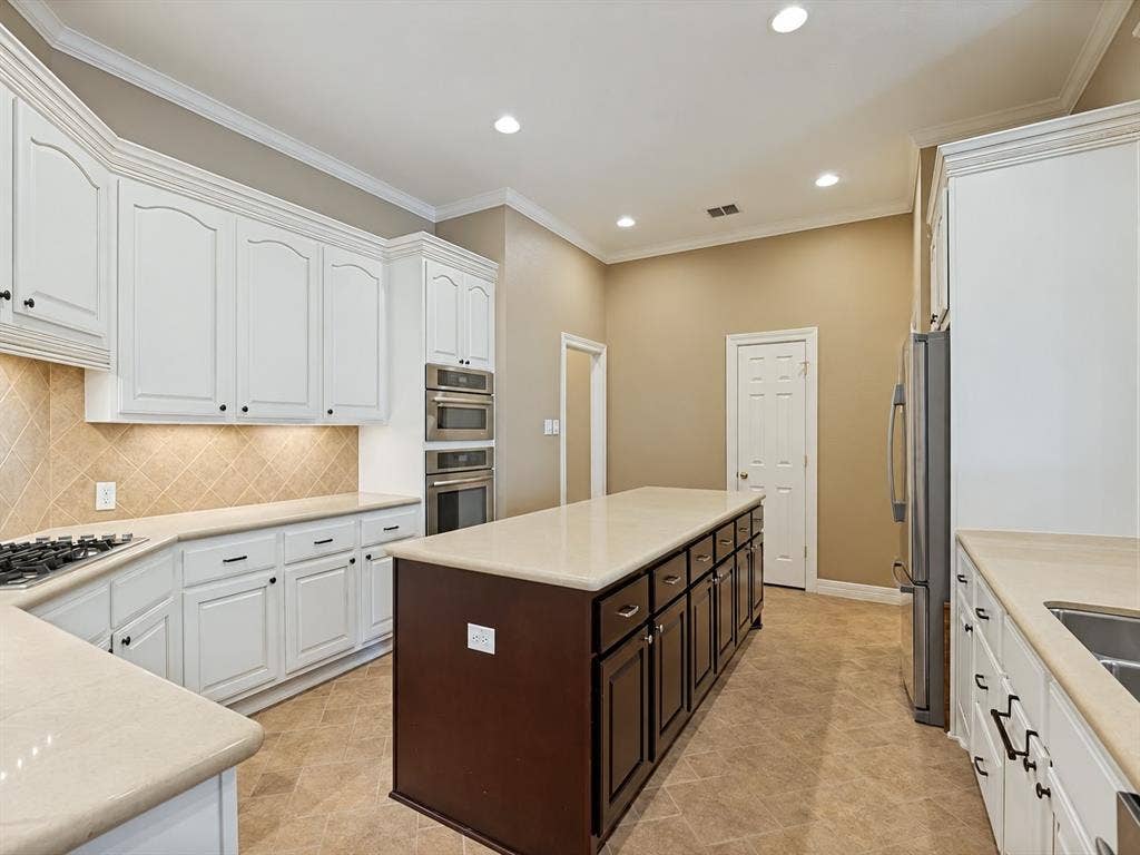 604 Barkley Drive, McKinney, TX 75071 Kitchen featuring white upper cabinetry, a contrasting dark wood-finish center island, stone-surface countertops, tile backsplash, and built-in stainless steel double wall ovens