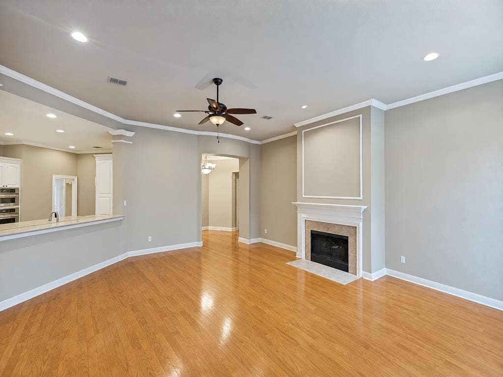 604 Barkley Drive, McKinney, TX 75071 Living space featuring wood-finish flooring, a fireplace with a decorative mantel, crown molding, recessed lighting, and a ceiling fan