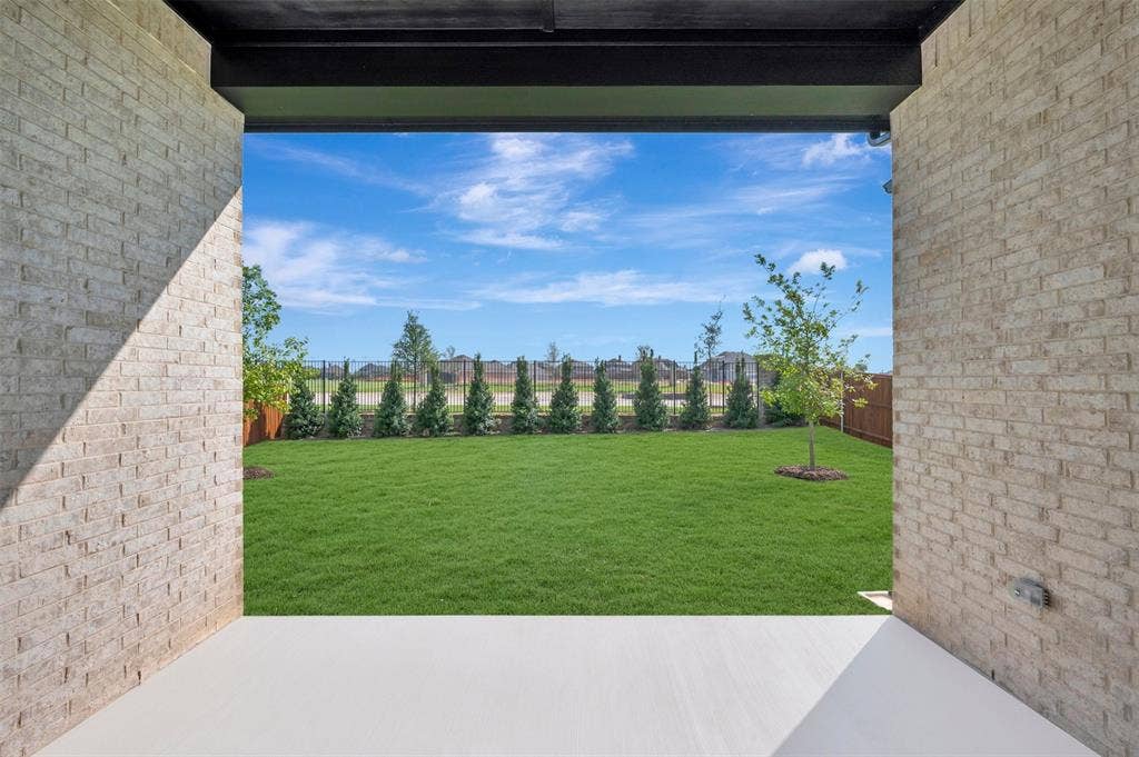 3469 Jersey Drive, Midlothian, TX 76065 Covered patio featuring brick exterior walls and concrete flooring, opening to a fenced backyard with mature trees and landscaping