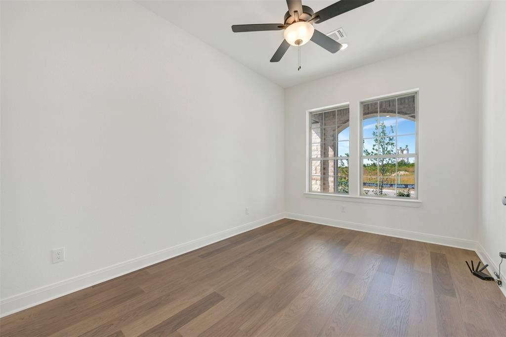 3469 Jersey Drive, Midlothian, TX 76065 Wood-finish flooring, dual windows with arched masonry trim, and a ceiling-mounted fan with integrated lighting