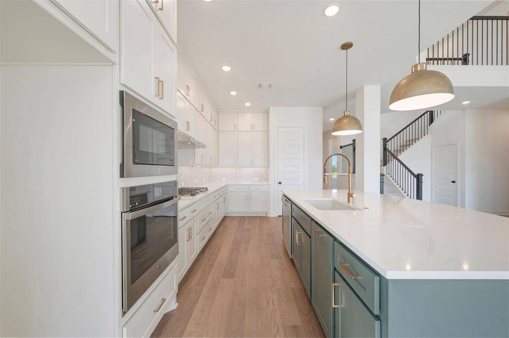 3469 Jersey Drive, Midlothian, TX 76065 Kitchen featuring an oversized center island with stone-surface countertop, stainless steel double wall ovens, wood-finish flooring, and recessed lighting