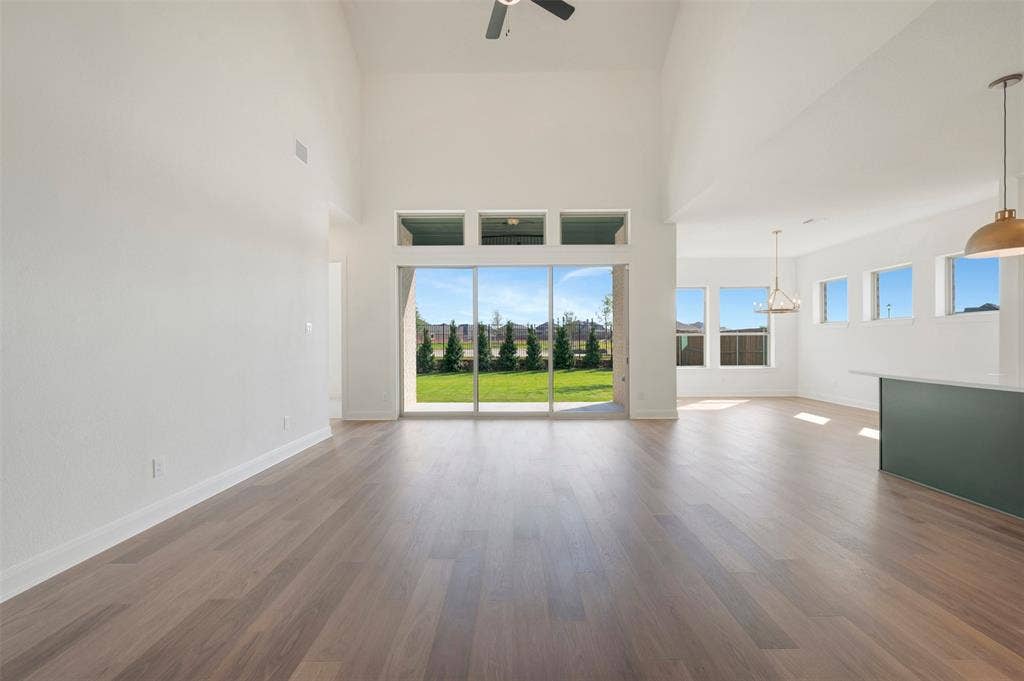 3469 Jersey Drive, Midlothian, TX 76065 Vaulted ceilings, wood-finish flooring, expansive sliding glass doors, multiple pendant light fixtures, and a center island with a stone countertop