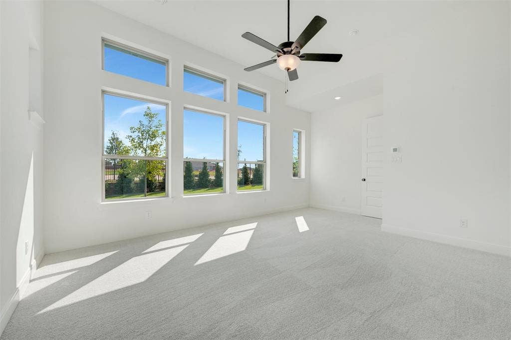 3469 Jersey Drive, Midlothian, TX 76065 High ceilings featuring a matte black ceiling fan with an integrated light fixture, large paneled windows, and neutral carpeting
