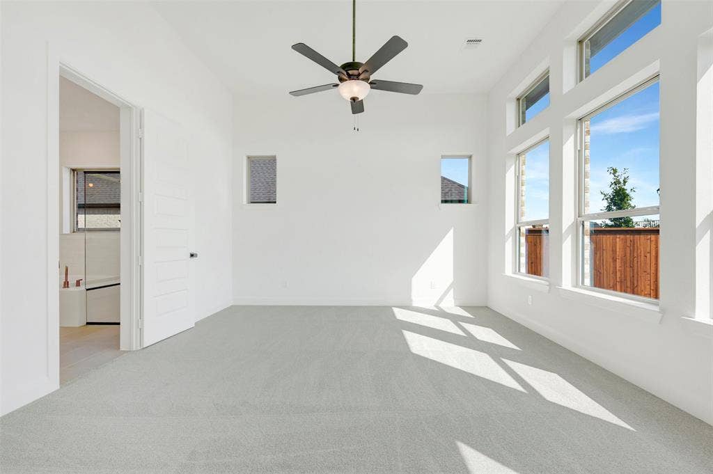 3469 Jersey Drive, Midlothian, TX 76065 High-ceiling room featuring neutral carpeting, a central multi-blade ceiling fan with integrated lighting, oversized windows, and a multi-panel door