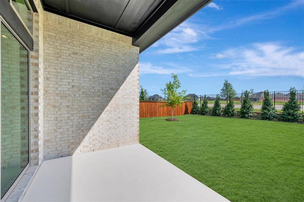 3469 Jersey Drive, Midlothian, TX 76065 Covered patio featuring a light brick exterior wall, full-height glass door, manicured lawn, wood-panel fencing, and perimeter evergreen landscaping