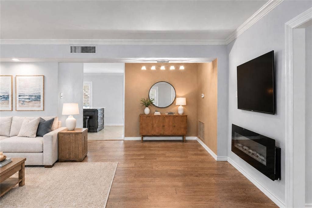 8629 Edgemere Road, #13, Dallas, TX 75225 Living area featuring wood-finish flooring, a wall-mounted electric fireplace, crown molding, and a multi-light flush-mount fixture