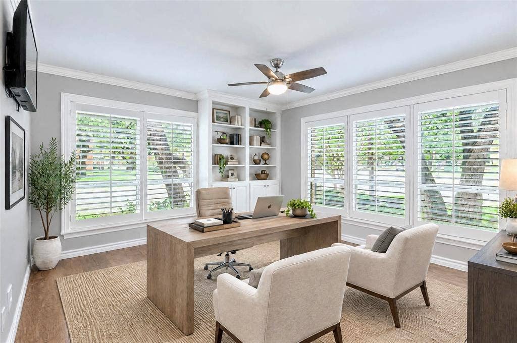 8629 Edgemere Road, #13, Dallas, TX 75225 Room featuring wood-finish flooring, built-in floor-to-ceiling shelving, triple-window configuration with white plantation shutters, and a central ceiling fan with integrated lighting