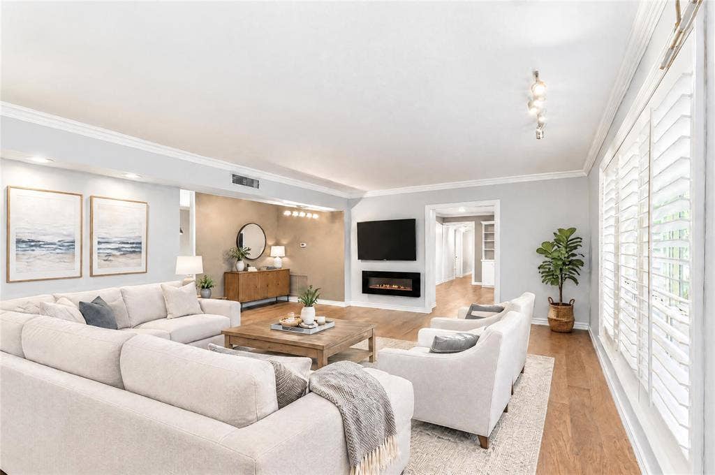8629 Edgemere Road, #13, Dallas, TX 75225 Living area featuring wood-finish flooring, crown molding, plantation shutters, and a wall-mounted electric fireplace