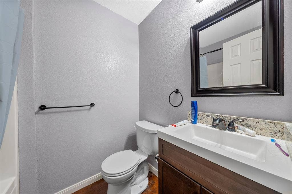 2125 Burnett Avenue, Waco, TX 76706 Unit A Bathroom featuring a dark wood-finish vanity, stone-patterned countertop with integrated sink, matte black hardware, and framed wall mirror