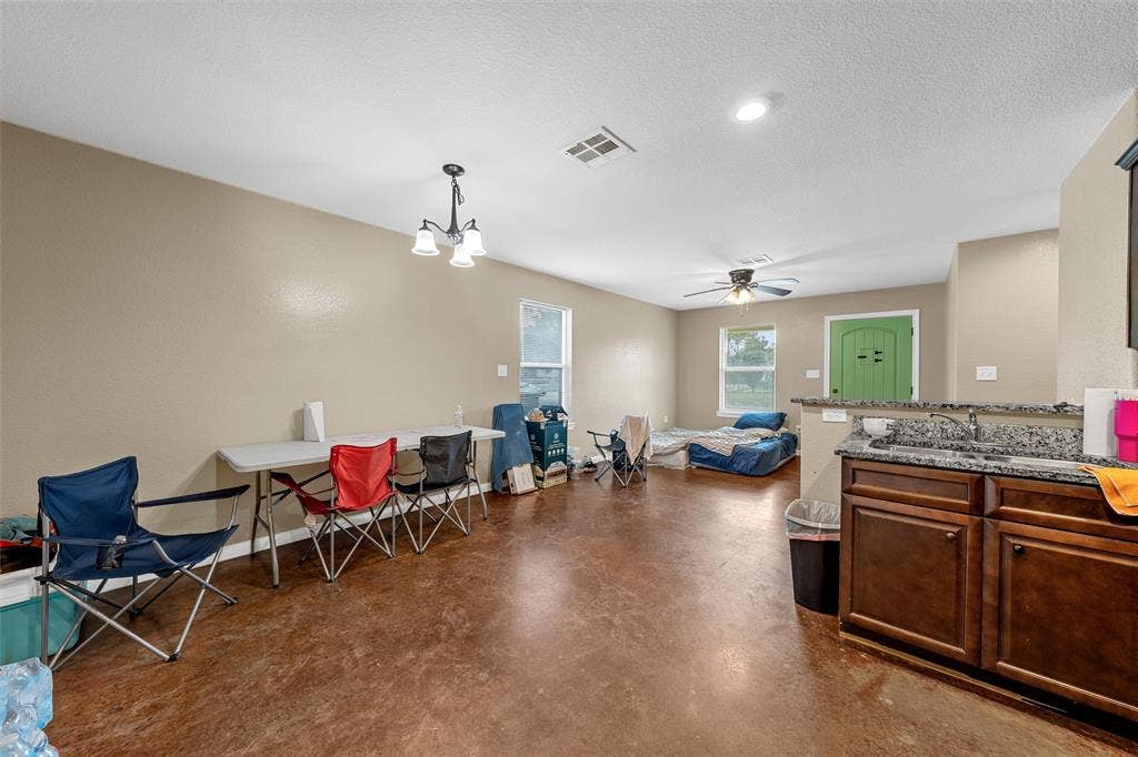 2125 Burnett Avenue, Waco, TX 76706 Unit B Open-concept interior featuring stained concrete flooring, stone-finish countertops, dark wood-tone cabinetry, recessed lighting, and a multi-light chandelier