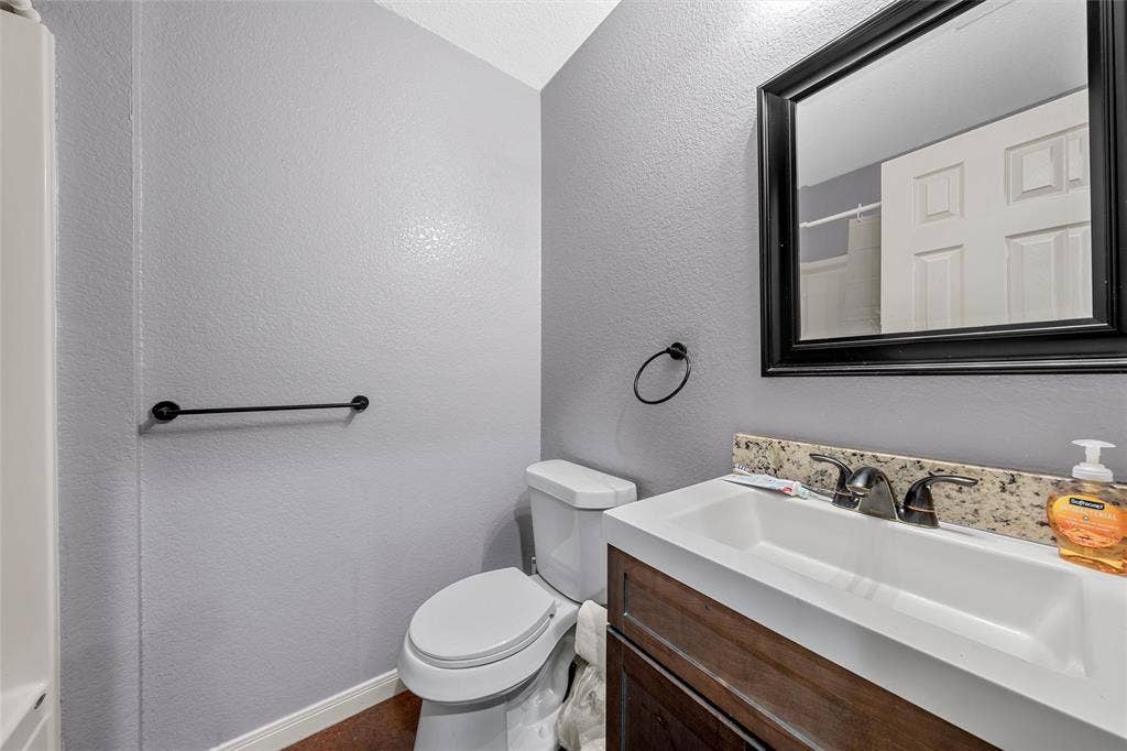 2125 Burnett Avenue, Waco, TX 76706 Unit A Vanity featuring a dark wood-finish cabinet, stone countertop with integrated basin, matte black faucet, and matching framed wall mirror