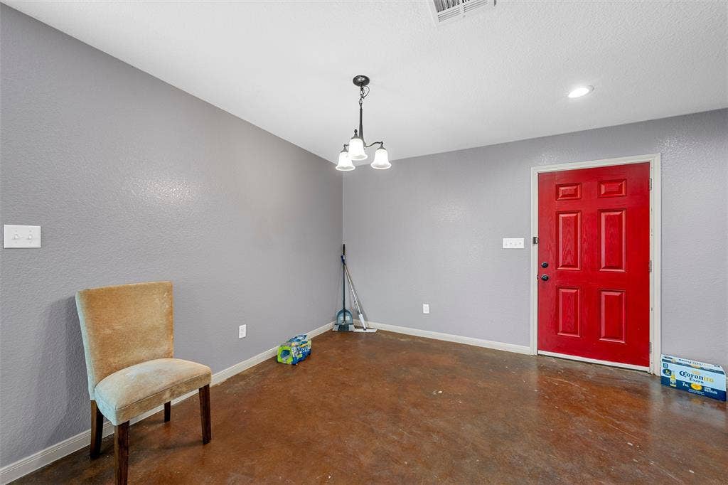2125 Burnett Avenue, Waco, TX 76706 Unit A Neutral gray walls, six-panel red entry door, stained concrete flooring, and three-light ceiling-mounted fixture