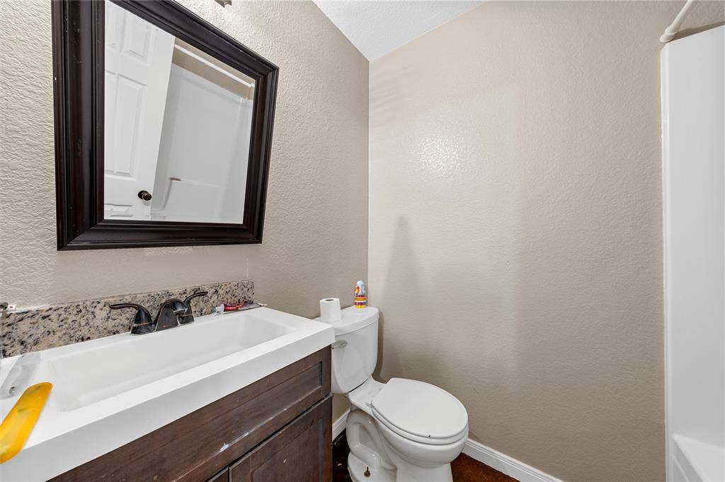 2125 Burnett Avenue, Waco, TX 76706 Unit B Bathroom featuring a vanity with a stone-finish countertop, undermount sink, dark wood-tone cabinetry, and a framed wall-mounted mirror