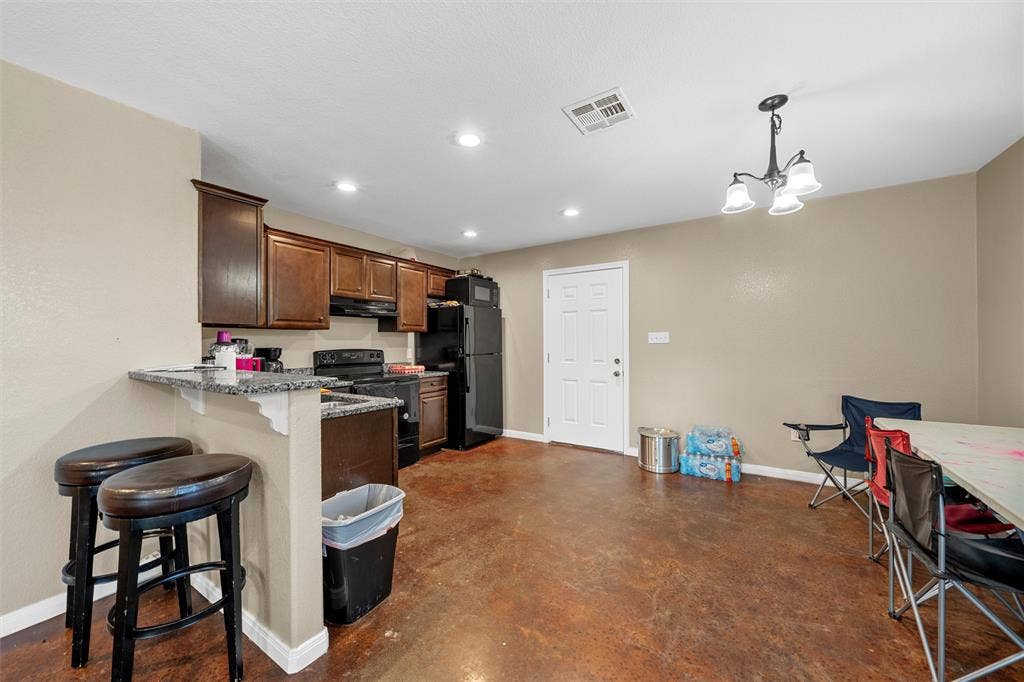 2125 Burnett Avenue, Waco, TX 76706 Unit B Kitchen featuring dark-stained cabinetry, granite-finish countertops, a breakfast bar, recessed lighting, and stained concrete flooring