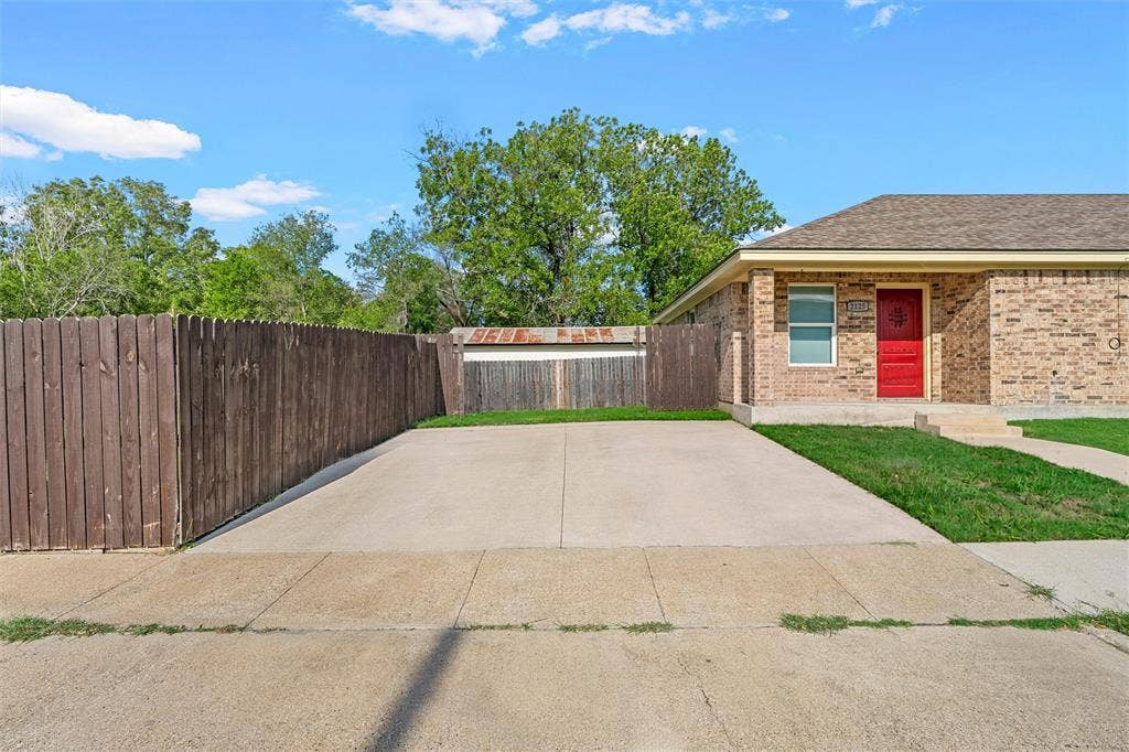 2125 Burnett Avenue, Waco, TX 76706 Unit A Brick exterior residence featuring a dedicated concrete driveway, private wooden perimeter fencing, and an entry door