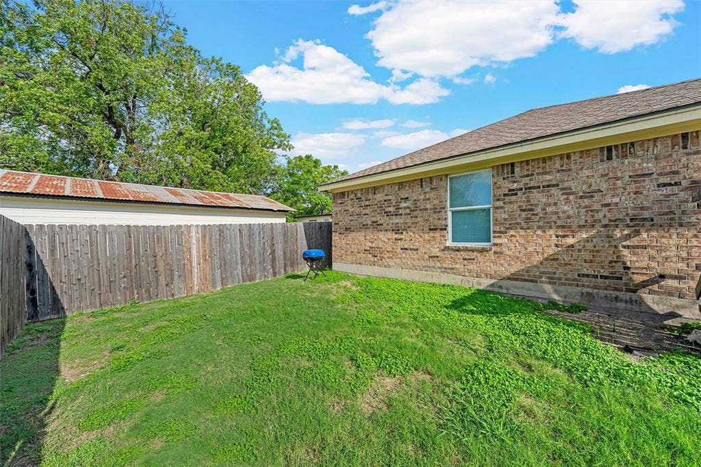 2125 Burnett Avenue, Waco, TX 76706 Unit A Rear exterior featuring a brick facade, single-hung window, and vertical wood fencing