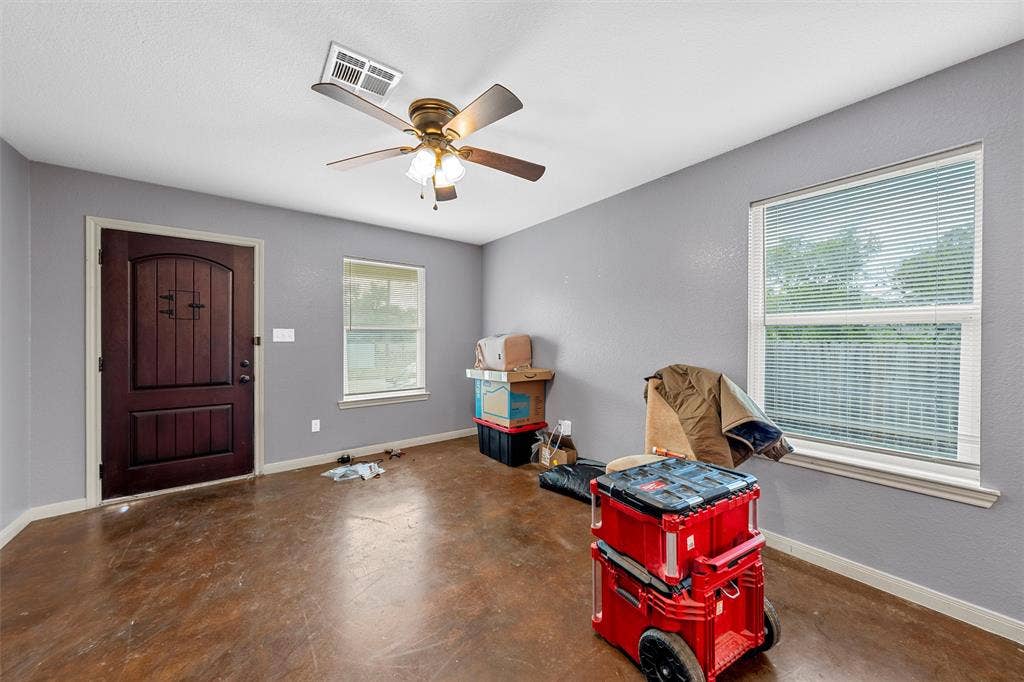 2125 Burnett Avenue, Waco, TX 76706 Unit A Interior space featuring stained concrete flooring, dark wood-finish door with decorative hardware, multi-light ceiling fan, and dual windows